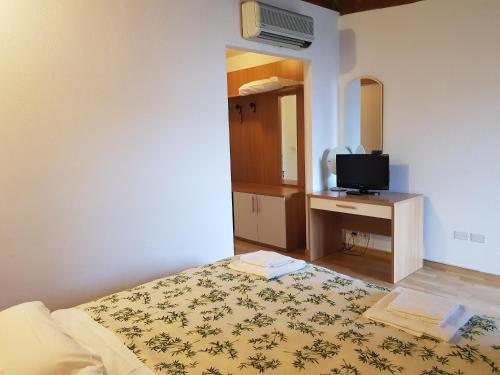 a bedroom with a bed and a tv on a desk at Hotel Oasi in Muggia