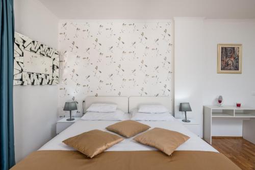 a white bedroom with a bed with two pillows at Villa Voinic 3 in Cavtat