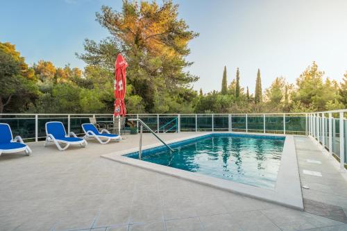 a swimming pool with two chairs and a umbrella at Villa Voinic 3 in Cavtat