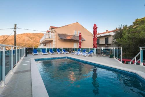 a swimming pool with chairs and a house at Villa Voinic 3 in Cavtat