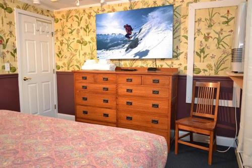 a bedroom with a dresser and a tv on the wall at Luxurious Trailside Village One Bedroom Condo #1 in Killington