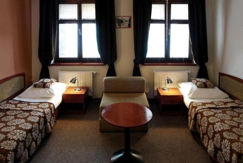 a room with two beds and a chair and a table at Hotel Pod Hradom in Trenčín