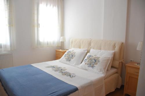 1 dormitorio con 1 cama con sábanas y almohadas blancas y azules en Villa Sofia, en Parga