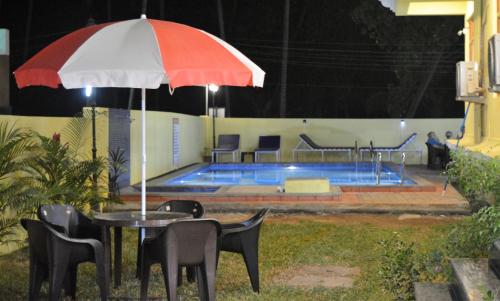 a table with an umbrella in front of a pool at Sonikas Leisure in Candolim