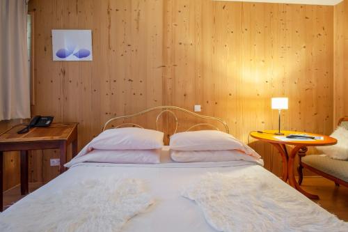 a bed in a room with a wooden wall at La Ferme de Thoudiere in Saint-Étienne-de-Saint-Geoirs