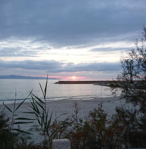 a sunset over the ocean with a pier in the distance at Borgo Bellavista Isola Rossa in Isola Rossa