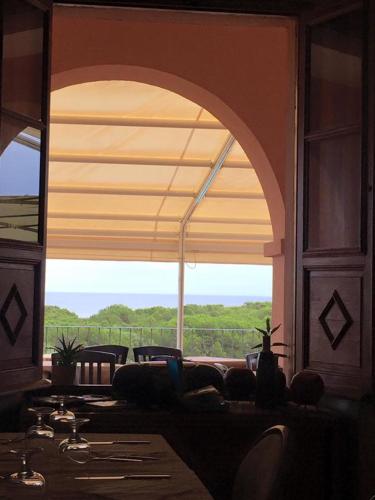 a room with a large window with a table and chairs at Hotel Villa Campana in Cala Liberotto
