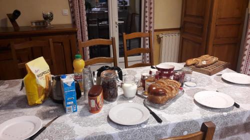 VaulxにあるChez Michelle et Dany - Chambres d'hôtes proche d'Annecyのテーブルクロスがかけられ、食べ物と皿が置かれたテーブル