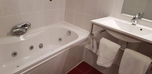 ein Badezimmer mit einer weißen Badewanne und einem Waschbecken in der Unterkunft Le Médoc de Maxou in Lamarque