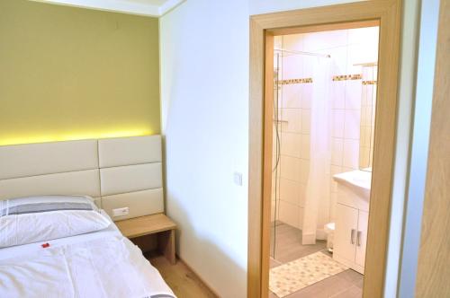 a small bedroom with a bed and a shower at Apartments Jernej am Turnersee in Sankt Kanzian