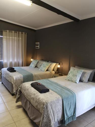two beds in a hotel room withskirts at Elim Guesthouse in Keimoes