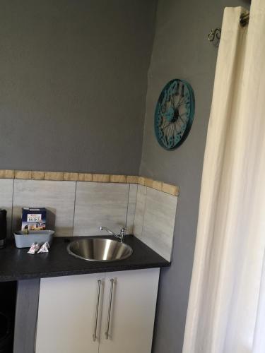 a bathroom with a sink and a clock on the wall at Elim Guesthouse in Keimoes
