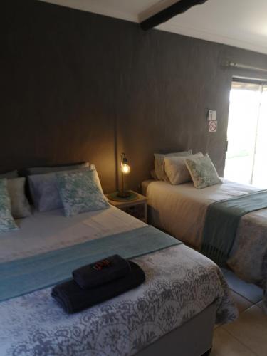 a bedroom with two beds and a lamp on a table at Elim Guesthouse in Keimoes