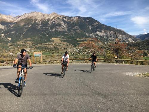 three people riding bikes down a road with mountains in the background at Studio Chez Mary in Chorges