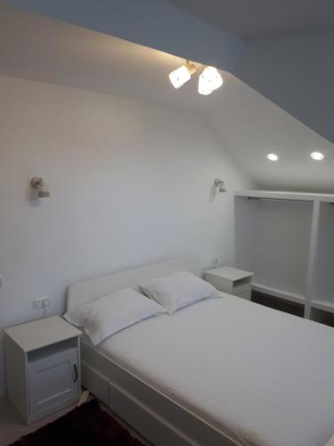 una camera da letto con un grande letto bianco con due tavoli di Iarca Cottage a Bucarest