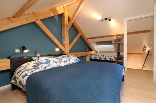 a bedroom with a blue bed and wooden beams at Le Grenier du 11 in Gérardmer