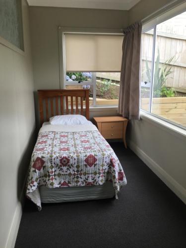 a bedroom with a bed with a quilt and a window at 4 Parris St in New Plymouth