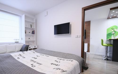 a bedroom with a bed and a flat screen tv at Apartimento Naturale in Wrocław