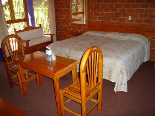 a bedroom with a bed and two chairs and a table at Hotel Bella Vista in Huasca de Ocampo