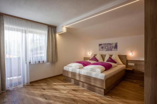 a bedroom with a bed with purple pillows and a window at Ferienwohnungen Obinghof in Söll