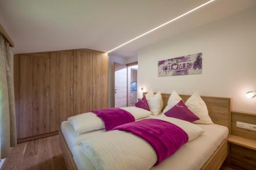 a bedroom with a large bed with purple and white pillows at Ferienwohnungen Obinghof in Söll