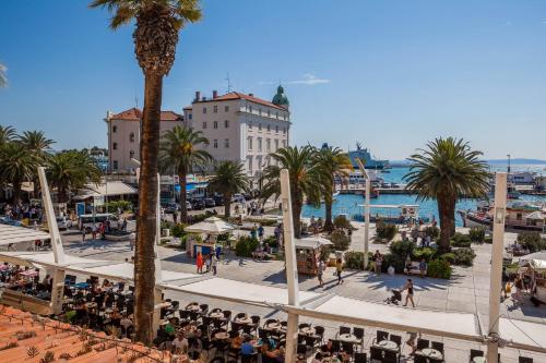 a group of people sitting in chairs in a town with palm trees at Guest House Imperial in Split