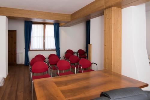 a conference room with red chairs and a wooden table at Al Sole Hotel Ristorante dal 1870 in Pieve di Cadore