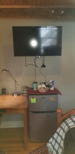 a bedroom with a desk and a television on the wall at Hallowell Rooming House in Hallowell