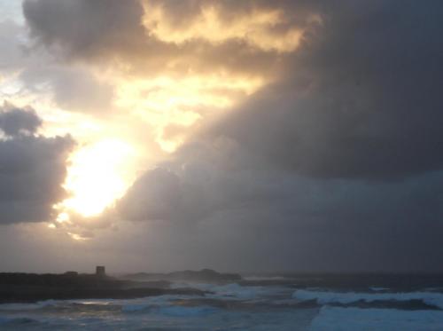 a cloudy sky over the ocean with the sun poking through at Hotel da Paolino in Trinità dʼAgultu
