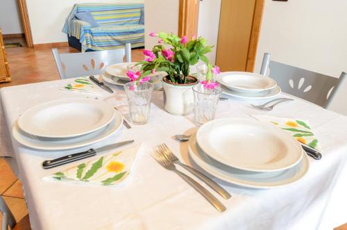 a table with plates and utensils and flowers on it at Le Tartarughe Aparthotel in Letojanni