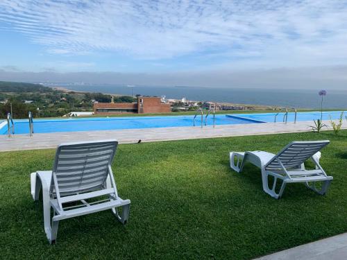 twee stoelen op het gras bij een zwembad bij SYRAH Vistas by depptö in Punta del Este