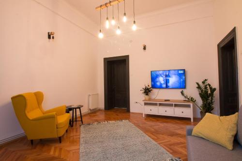 a living room with a tv and a yellow chair at Muresenilor 28 in Braşov