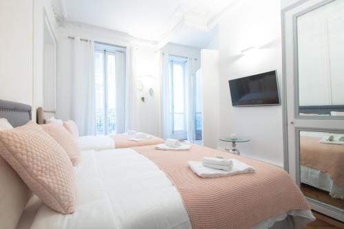 a white bedroom with two beds and a flat screen tv at Dreamyflat - Champs Élysées in Paris