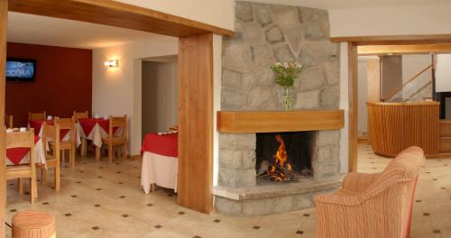 a fireplace in a restaurant with tables and chairs at Hostería Antu Kuyen in San Carlos de Bariloche