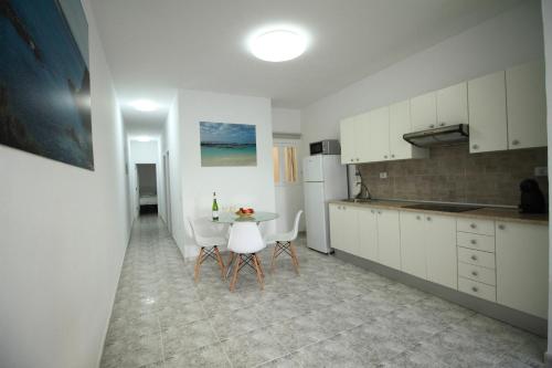 a kitchen with white cabinets and a table and chairs at COTILLO SEA in Cotillo
