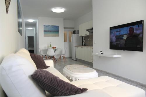 a living room with a white couch and a flat screen tv at COTILLO SEA in Cotillo