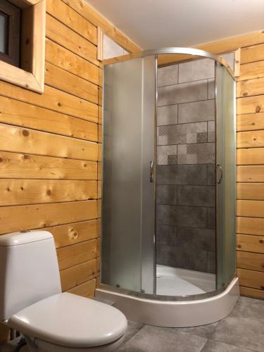 a shower in a bathroom with wooden walls at RIVIERA in Lekechi