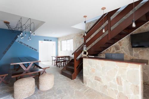 a living room with a staircase and a tv at BRECHA HOSTEL & ROOFTOP - Maragogi in Maragogi