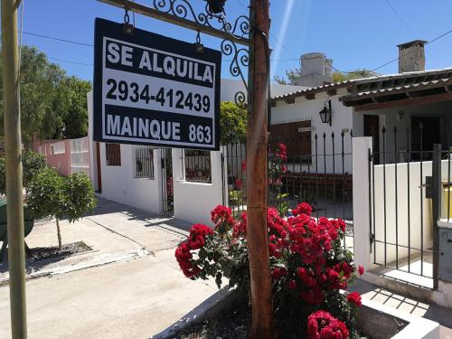 Un cartel en la calle frente a un edificio con flores. en Alojamiento Turistico Mainque, en Las Grutas