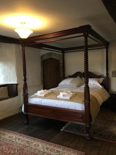 a bedroom with a canopy bed with white sheets at Great House Guest House in Llantwit Major