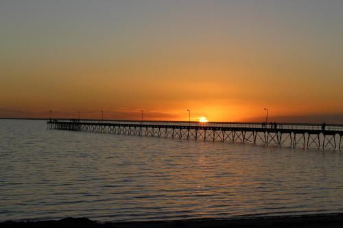 a pier with the sunset in the background at Ceduna Foreshore Caravan Park in Ceduna