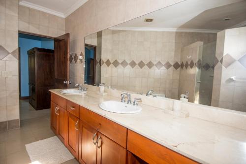 baño con 2 lavabos y espejo grande en Macaws Ocean Club Apartamento # 18, en Jacó