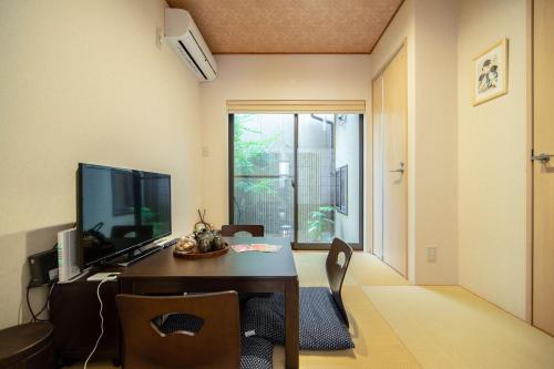 a dining room with a table and a television at EnSe Higashi Hongan-ji Villa in Kyoto