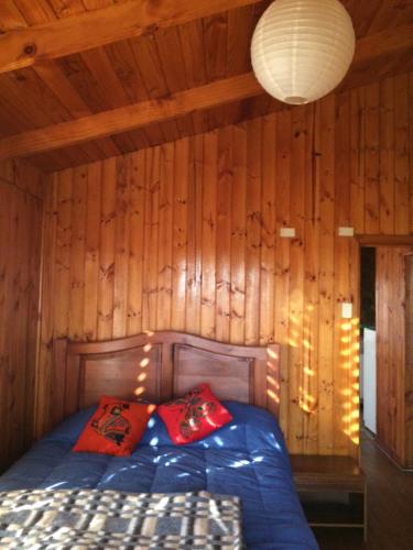 a bedroom with a bed with a wooden wall at CASA EN PALAFITO in El Quisco