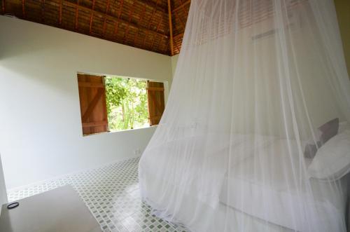 a bedroom with a bed with a mosquito net at Maison de l'Amant in Cai Be