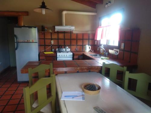 cocina con mesa, sillas y heladera en Zahra Depto en Villa Gesell