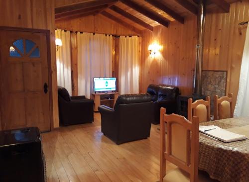 a living room with leather furniture and a television at Cabaña en Dalcahue in Dalcahue