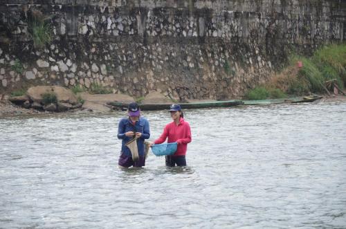two people standing in the water in a river at Saksiri Riverside Boutique Hotel in Vang Vieng