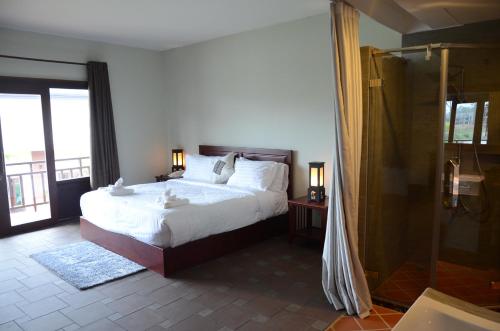 a bedroom with a bed and a glass shower at Saksiri Riverside Boutique Hotel in Vang Vieng