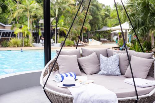 a swinging couch with a hat on it next to a pool at Angourie Resort in Yamba